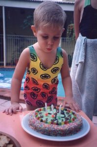 child blowing out candles on decorated cake